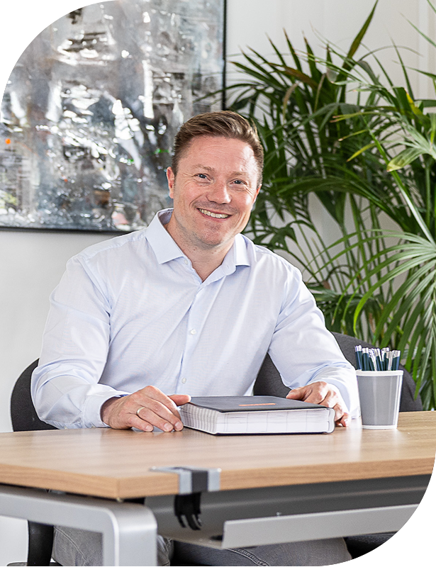 Smiling man at desk with notebook and plant