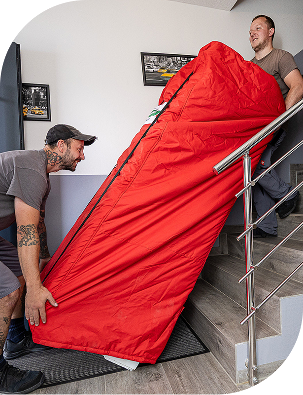 Two men carrying large red bag upstairs