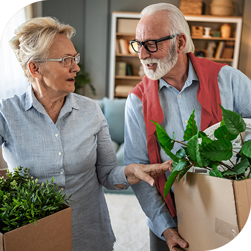 Senior couple holding moving boxes with houseplants